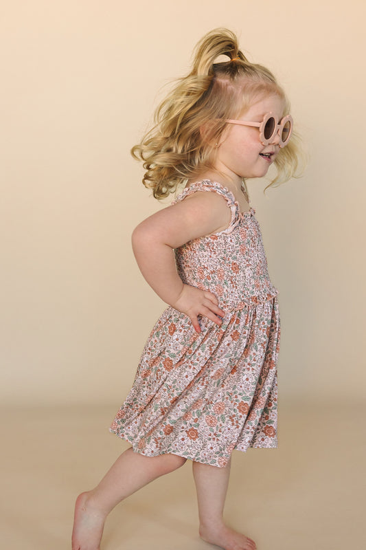 Smiling toddler wearing a floral bamboo twirl dress with flutter straps in Vintage Bloom print.
