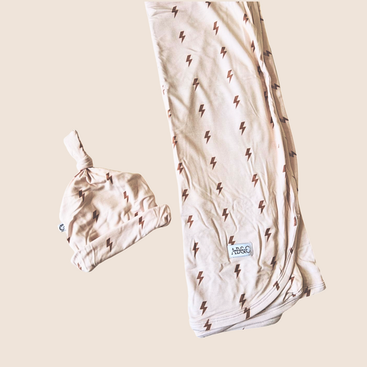 Baby hat and swaddle with lightning bolt pattern on a beige background